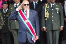 FILE - In this Aug. 12, 2015, file photo, Suriname President Desire Delano Bouterse salutes during a military parade, after being sworn in for his second term, in Paramaribo, Suriname. A two-time coup leader and former dictator accused of executing 15 political opponents in 1982, Bouterse has again moved on Wednesday, June 29, 2016, to prevent authorities in the South American nation from putting him on trial for those 15 deaths. (AP Photo/Ertugrul Kilic, File)