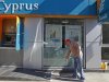 A worker sweeps in front of a branch of Bank of Cyprus in Bucharest