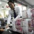 An employee hands Renminbi banknotes to a customer at a branch of the Industry and Commercial Bank of China in Hefei