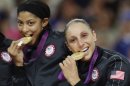 United States' Diana Taurasi, right, and Candace Parker bite their gold medals after beating France in the women's gold medal basketball game at the 2012 Summer Olympics, Saturday, Aug. 11, 2012, in London. (AP Photo/Charles Krupa)