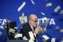 FIFA president Sepp Blatter is photographed while banknotes thrown by British comedian Simon Brodkin hurtle through the air during a press conference following the extraordinary FIFA Executive Committee at the headquarters in Zurich, Switzerland, Monday, July 20, 2015. During the extraordinary FIFA Executive Committee meeting the agenda for the elective Congress for the FIFA presidency was finalized and approved: The congress will take place on Feb. 26. 2016. (Ennio Leanza/Keystone via AP)