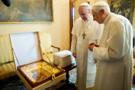 In this photo provided by the Vatican paper L'Osservatore Romano, Pope Francis, left, and Pope emeritus Benedict XVI meet in Castel Gandolfo Saturday, March 23, 2013. Pope Francis has traveled to Castel Gandolfo to have lunch with his predecessor Benedict XVI in a historic and potentially problematic melding of the papacies that has never before confronted the Catholic Church. The Vatican said the two popes embraced on the helipad. In the chapel where they prayed together, Benedict offered Francis the traditional kneeler used by the pope. Francis refused to take it alone, saying "We're brothers," and the two prayed together on the same one. (AP Photo/Osservatore Romano, HO)