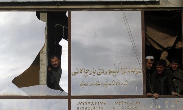 Afghan men look out a window …