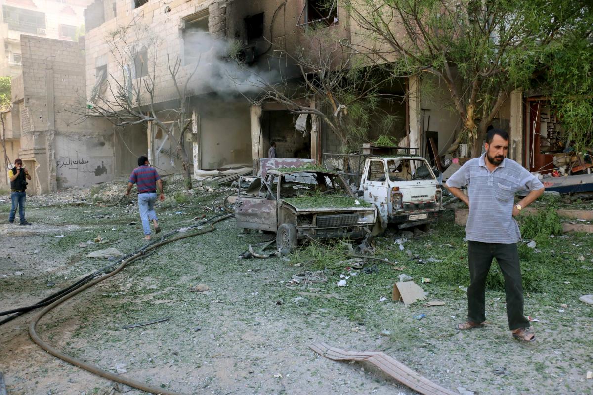 Civilians inspect a damaged site after what activists said were airstrikes by forces loyal to Syria&#39;s President Bashar al-Assad in the Damascus suburb of Ain Tarma