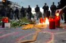 People light candles in front of riot policemen to commemorate policemen killed after fighting between Macedonian police and an armed group in the town of Kumanovo, in Skopje on May 11, 2015