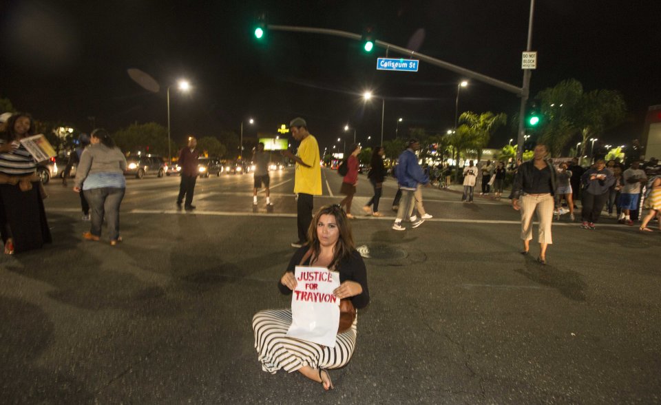 A demonstrator with a sign sits on the intersection of Crenshaw Boulevard and Coliseum street during a protest in Los Angeles on Sunday, July 14, 2013, the day after George Zimmerman was found not guilty in the shooting death of Trayvon Martin. Seventeen-year-old Martin was shot and killed in February 2012 by neighborhood watch volunteer George Zimmerman. (AP Photo/Ringo H.W. Chiu)