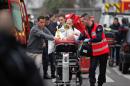 FILE - In this Wednesday Jan. 7, 2015, file photo, an injured person is transported to an ambulance after a shooting at the French satirical newspaper Charlie Hebdo's office in Paris, France. Though it is impossible to gauge in any tangible way the effect the deadly attack on a Paris newspaper will have on recruitment by extremist groups - and there is no evidence so far that it is mobilizing large numbers of would-be jihadis - experts believe the perceived professionalism of the brothers' assault and their subsequent showdown with police could rally more supporters to militant ranks. (AP Photo/Thibault Camus)