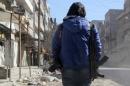 A young Syrian journalist carries a camera and a gun to protect himself, on February 9, 2014 in a street in Aleppo