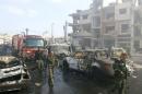 Syrian army soldiers inspect the site of a two bomb blasts in the government-controlled city of Homs