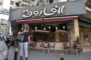 In this Monday, Sept. 30, 2013 photo, a Lebanese woman walks past the Syrian Al-Farouk restaurant in Hamra Street, Beirut, Lebanon. On Hamra street, some stores and restaurants including Damascus' famous Al-Farouk food establishment that relocated to Beirut earlier this year almost exclusively employ Syrians, including chefs, waiters, managers, and cleaners. Lebanon's market is flooded with Syrian refugees in desperate need of work, their cheap labor force posing an additional problem to the Lebanese economy that has struggled with billions of losses from spillover effects of the Syrian conflict. (AP Photo/Bilal Hussein)