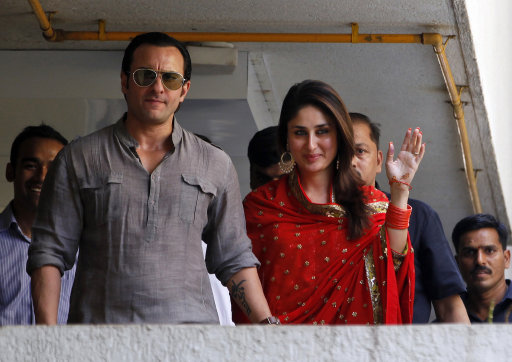 Bollywood stars Saif Ali Khan, left, and Kareena Kapoor step out on a balcony to greet waiting fans after getting married in Mumbai, India, Tuesday, Oct. 16, 2012. The Press Trust of India reported the couple married Tuesday in a small official ceremony in Khan’s house in Mumbai with a few friends and family members in attendance.  (AP Photo/ Rajanish Kakade)