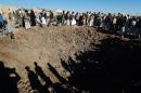 Yemenis gather around a crater reportedly caused by a Saudi-led airstrike on the outskirts of the capital Sanaa on December 29, 2015