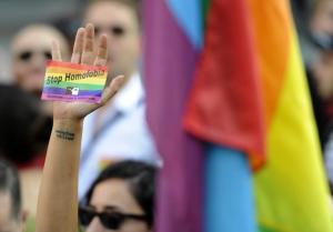 An activist brandishes a rainbow-flag sticker as he&nbsp;&hellip;
