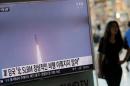 A passenger walks past a TV screen at a railway station in Seoul, South Korea, broadcasting a news report on North Korea's submarine-launched ballistic missile fired from North Korea's east coast port of Sinpo