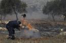 A Palestinian tries to put out the fire in an olive grove in the West Bank village of Jaloud, near Nablus, Wednesday, Oct . 9, 2013. Residents of the village said that masked Jewish settlers burst into a school, vandalized cars and torched olive trees during a rampage that forced schoolchildren to remain locked in classrooms to keep safe. (AP Photo/Nasser Ishtayeh)