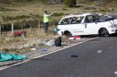 Policemen examine the scene of a minivan crash near Turangi, New Zealand, Saturday, May 12, 2012. Three Boston University students who were studying in New Zealand were killed Saturday when their minivan crashed. At least five other students from the university were injured in the accident, including one who was in critical condition. (AP Photo/New Zealand Herald, John Cowpland) NEW ZEALAND OUT, AUSTRALIA OUT