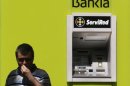 Man stands next to Bankia bank ATM in Madrid