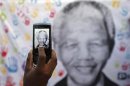 A well-wisher takes a picture of a banner featuring Mandela during his birthday in Pretoria