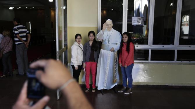 In this June 7, 2015 photo, tourists take pictures with a life-size cutout poster of Pope Francis after attending Mass celebrating the feast day of Corpus Cristi at the Basilica of the Virgin of Caacupe in Caacupe, Paraguay. On July 11, Francis will celebrate Mass in the square in front of this basilica, in part to accommodate the hundreds of thousands of people expected to attend. (AP Photo/Jorge Saenz)