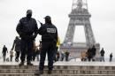 Police officers patrol in front of the Eiffel Tower on November 18, 2013 in Paris, while a frantic manhunt was underway for a shooter