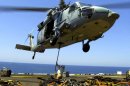 This US Navy photo received 26 March 2004, shows a US Marine aboard USS Wasp and an MH-60S Knighthawk helicopter