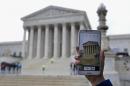 A Supreme Court visitor takes pictures with her cell phone outside the Supreme Court in Washington, Tuesday, April 29, 2014, during a hearing. The Supreme Court is considering whether police may search cellphones found on people they arrest without first getting a warrant. ( AP Photo/Jose Luis Magana)
