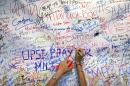 A woman writes her a message of support for family members of passengers onboard the missing Malaysia Airlines Flight MH370 in Sepang