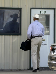 A law enforcement officer, left, walks into the office of Gibson Self Storage where he met with property manager Larry Mathis on Monday, April 15, 2013, in Seagoville, Texas. The facility was searched over the weekend by authorities in addition to the home of Eric Lyle Williams. Texas authorities investigating the killings of a district attorney and his wife are working to build a case against a former justice of the peace prosecuted last year by the slain official's office, a law enforcement official said Monday. (AP Photo/Tony Gutierrez)