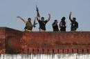 Indian security personnel celebrate on the roof of a police station after a gunfight in Dinanagar town, India
