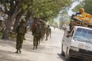 Soldiers, who are serving with the Kenyan Contingent of the African Union Mission in Somalia, patrol along a street as a commuter taxi passes by in Kismayo