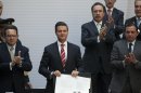 Flanked by Mexican Senate Deputy Chairman Francisco Arroyo Vieira, left, and Mexican Senate President Ernesto Cordero, right, Mexico's President Enrique Pena Nieto, center, shows off the signed document enacting education reform, at the National Palace in Mexico City, Monday, Feb. 25, 2013. The law which was approved by Congress in December, calls for creation of a professional system for hiring, evaluating and promoting teachers without the "discretionary criteria" currently used in a system where teaching positions are often bought or inherited. (AP Photo/Alexandre Meneghini)