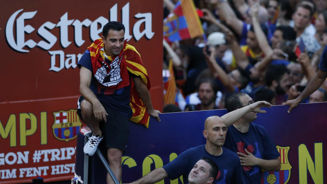 Barcelona&#39;s Xavi Hernandez, top left, rides on the team bus during celebrations in Barcelona, Spain Sunday June 7, 2015 after winning the Champions League final soccer match Saturday by beating Juventus Turin 3-1. Barcelona won the triple this season winning the Spanish League title, the Copa del Rey and the Champions League. (AP Photo/Manu Fernandez)