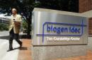 A pedestrian passes the sign outside the headquarters of Biogen Idec Inc. in Cambridge