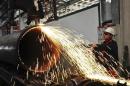 A worker operates a machine to cut a pipeline at a factory in Qingdao