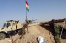 Kurdish Peshmerga forces raise the Kurdish flag at a checkpoint on the road leading from Kirkuk to northern Iraqi city of Tikrit on June 30, 2014