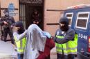 Masked Spanish police officers take an arrested person from an undisclosed location for suspected links to Al-Qaeda and the Islamic State on February 7, 2016