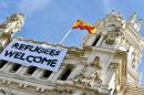 A Spanish flag flies above a banner reading "Refugees Welcome" hanging on the facade of the Cibeles Palace, the Madrid City Hall, on September 7, 2015