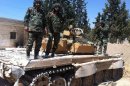 Syrian soldiers stand on top of a tank in the Eastern Ghouta area on the outskirts of Damascus on August 30, 2013
