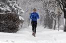 A jogger runs on a snowy sidewalk in Evanston, Ill. on Saturday, Dec. 14, 2013. Snow continued to fall over the Chicago area into northwest Indiana. (AP Photo/Nam Y. Huh)