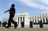 A police officer walks in front of the Federal Reserve in Washington August 22, 2012. REUTERS/Larry Downing