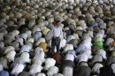 A man stands as Iranian worshippers perform prayers during the Muslim holy fasting month of Ramadan at the Tehran University campus, in Tehran, Iran, Friday, July 26, 2013. Muslims throughout the world are marking the month of Ramadan, the holiest month in Islamic calendar during which devotees fast from dawn till dusk. (AP Photo/Vahid Salemi, File)