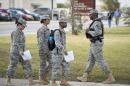 Soldiers walk past a military police officer, right, patrolling the perimeter of the US Army IMCOM HQ building prior to the Article 32 preliminary hearing to determine if Army Sgt. Bowe Bergdahl will be court martialed, Thursday, Sept. 17, 2015, at Fort Sam Houston in San Antonio. Bergdahl, who left his post in Afghanistan and was held by the Taliban for five years, is charged with desertion and misbehavior before the enemy. (AP Photo/Darren Abate)
