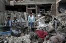 Men sit amid debris of their properties at the site a truck bomb blast in Kabul