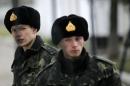 Ukrainian soldiers guard the gate of Ukraine's infantry base in Perevalne, Ukraine, Sunday, March 2, 2014. Hundreds of armed men in trucks and armored vehicles surrounded a Ukrainian military base Sunday in Crimea, blocking its soldiers from leaving. The outnumbered Ukrainians placed a tank at the base's gate, leaving the two sides in a tense standoff. (AP Photo/Darko Vojinovic)