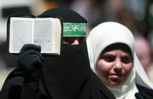 A Palestinian supporter of Hamas holds the Quran as &hellip;