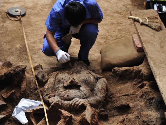A member of an archaeology team unearths a terracotta warrior at the excavation site inside the No.1 pit of the Museum of Qin Terracotta Warriors and Horses, on the outskirts of Xi'an, Shaanxi province, June 9, 2012. It is the first time that shields have been unearthed during an excavation. A large number of the terracotta warriors and horses bear traces of burn marks, which are suspected to have been caused by Xiang Yu, a military leader who rebelled against the Qin Dynasty (221 BC - 207 BC), according to local media. REUTERS/Stringer (CHINA - Tags: SOCIETY) CHINA OUT. NO COMMERCIAL OR EDITORIAL SALES IN CHINA