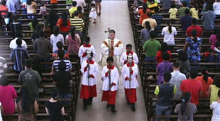 A priest and altar boys walk down the aisle after prayers were conducted during a mass service inside the church of Our Lady of Lourdes at Klang, outside Kuala Lumpur