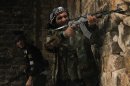 Free Syrian Army fighters take their positions as one of them fires during clashes with forces loyal to Syria's President Assad in Qastal Harami area in Aleppo
