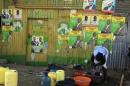 A woman washes her clothes by a wall with various campaign posters in the Kibera slum in Nairobi