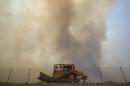 Smoke rises behind a firefighting bulldozer as a wildfire driven by fierce Santa Ana winds blows in Rancho Cucamonga, California.